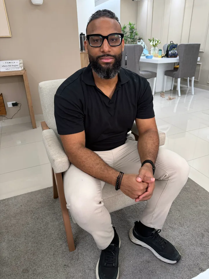 Foto real de Yeison sentado en un sillón, de cuerpo entero